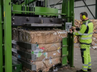 Industrijski balirni stroj med stiskanjem kartonskih odpadkov v bale v tovarni